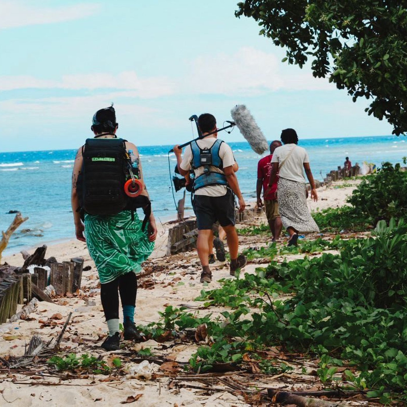 A film crew walking the beach with camera gear