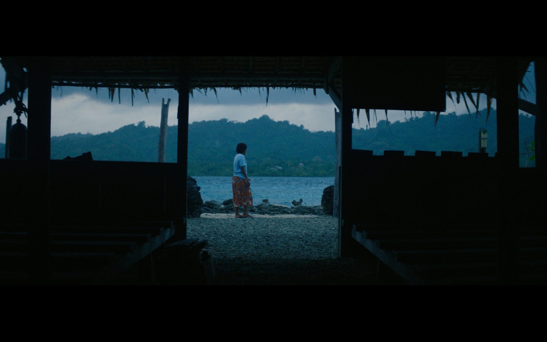 A woman standing in a doorway looking out over the water